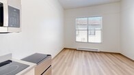 Located at 833 Front St. in downtown Santa Cruz, California, this thoughtfully laid-out unit offers a clean, minimalist aesthetic across its single floor. The space is organized into three distinct areas, each designed for practical everyday living.

The main living area features light-toned hardwood-style flooring that runs throughout the unit, crisp white walls, and a window fitted with blinds that allows natural light to fill the room. A baseboard heater runs along the exterior wall, ensuring year-round comfort. The open, uncluttered design gives the space a bright and airy feel.

The kitchenette is efficiently appointed with light wood cabinetry, a stainless steel single-basin sink, a smooth-top electric cooktop, and an over-the-counter stainless steel microwave. The neutral gray countertops complement the cabinetry, creating a cohesive and modern look. A closet is accessible just off the kitchen area, providing additional storage.

The bathroom is clean and functional, featuring a full-size soaking tub with an overhead shower and curved curtain rod, chrome fixtures, a toilet, and a towel bar — all set against white walls and matching wood-style flooring. The consistent flooring and white palette throughout the unit create a unified, orderly ambiance well-suited for efficient urban living in the heart of Santa Cruz.
