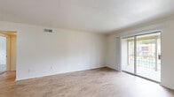 This single-floor, 2-bedroom, 1-bathroom unit offers a functional and well-organized layout designed for comfortable everyday living. The open living room is a bright, welcoming space featuring light wood-look flooring, crisp white walls, and a sliding glass door that fills the area with natural light and provides direct access to an outdoor patio. The living area flows into the kitchen via a convenient pass-through counter with a granite-style surface, offering an open connection between the two spaces. The kitchen is equipped with warm wood cabinetry, a granite countertop, and black appliances, including a full-size refrigerator. A hallway connects the main living areas to the private quarters of the home. Both bedrooms are finished with plush, neutral-toned carpet and bright white walls, creating a calm and restful atmosphere. The primary bedroom is a generously sized room, while the secondary bedroom features a window that lets in natural light and views of the surrounding area. Both bedrooms are outfitted with built-in closets featuring bi-fold doors, providing ample storage. The shared bathroom includes a full tub and shower combo with warm earth-toned tile surround, a wood vanity with granite countertop, and wood-look flooring, completing the unit's cohesive and clean aesthetic.