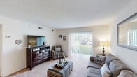 This single-story home in Augusta, Georgia offers a well-organized layout across three bedrooms and one bathroom. The inviting living room features soft carpeting, a textured ceiling, and a sliding glass door that floods the space with natural light and provides direct access to an outdoor patio with green views. The combined dining and kitchen area is a functional hub, featuring warm wood cabinetry, granite-style countertops, a full-size refrigerator, and a dedicated dining space with room for a full table. The three bedrooms are carpeted and bright, each with windows that bring in natural light. The spacious primary bedroom comfortably accommodates a full bed and additional furnishings. A generous walk-in closet with built-in wire shelving and a hanging rod provides ample storage. The full bathroom is finished with tile flooring, wood cabinetry, a granite-style vanity countertop, and a shower-tub combination. A connecting hallway ties all rooms together efficiently. The home's clean, neutral palette and consistent carpeting throughout the living and sleeping areas create a cohesive and comfortable atmosphere well-suited for everyday living.