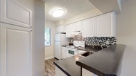 Located at 2545 NE Coachman Rd in Clearwater, Florida, this single-floor residence offers a well-appointed and functional layout designed for comfortable everyday living. The kitchen is a standout feature, showcasing crisp white cabinetry, dark granite-style countertops, a stainless steel double sink, and a striking mosaic tile backsplash in black, white, and gray tones. A full suite of white appliances — including a coil-top electric range and refrigerator — completes the space, which also benefits from a window that brings in natural light.

The living and dining areas are finished with durable wood-look vinyl plank flooring in a warm gray tone, lending a cohesive and contemporary feel throughout. Large windows dressed with horizontal blinds allow ample natural light to fill these open spaces, enhanced by a ceiling fan fixture.

The bedroom is carpeted for comfort and features neutral walls, a textured ceiling, and generous natural light from dual windows. A wide closet with louvered bifold doors and built-in wire shelving and hanging rods provides practical storage.

The bathroom is cleanly appointed with a white vanity, warm-toned countertop, a full tub-shower combination, and wood-look vinyl flooring, maintaining a consistent, tidy aesthetic throughout the home.