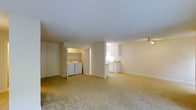 This single-floor residence offers a thoughtfully arranged open-concept layout that maximizes the sense of space and functionality. The main living area is finished with plush, neutral-toned carpeting that extends throughout, creating a warm and cohesive feel underfoot. Smooth white ceilings and soft, off-white walls contribute to a bright and airy ambiance, while track lighting provides focused illumination.

The kitchen is seamlessly integrated into the open plan and features white cabinetry, light-toned countertops, and under-cabinet lighting that keeps the workspace well-lit and practical. Its open-facing orientation connects naturally to the main living area, making it ideal for everyday use.

A dedicated in-unit laundry alcove is conveniently tucked adjacent to the living space, housing a full-size washer and dryer side by side—a practical and highly functional feature. Nearby, a set of bi-fold doors conceals additional closet storage, contributing to the space's organizational capacity.

The overall design is clean and understated, with a neutral palette that offers a versatile backdrop for a variety of interior styles. The open floor plan, combined with practical amenities and a single-level layout, makes this space both easy to navigate and comfortable for everyday living.