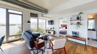 Located along the Anacostia waterfront in Washington, DC's vibrant Half Street corridor, this modern residence offers a sophisticated urban living experience defined by open-concept design and sweeping river views. The living area is anchored by floor-to-ceiling windows that flood the space with natural light and frame breathtaking panoramas of the water, while exposed industrial ductwork lends a loft-like aesthetic to the soaring ceilings. Warm hardwood flooring flows throughout, connecting the living and dining areas seamlessly. The dining space takes full advantage of its waterfront position, with large windows showcasing expansive river views — an ideal setting for entertaining. The kitchen is outfitted with crisp white shaker cabinetry extending to the ceiling, dark granite countertops, stainless steel appliances, and a marble-style backsplash. The bedrooms are generously proportioned, each featuring hardwood floors and large windows — one with a dramatic floor-to-ceiling view of the Potomac. Two bathrooms echo the home's refined palette, featuring dark granite vanity tops, white cabinetry, penny tile flooring, and clean, contemporary fixtures. This residence masterfully combines industrial-modern architecture with refined finishes and exceptional waterfront views.