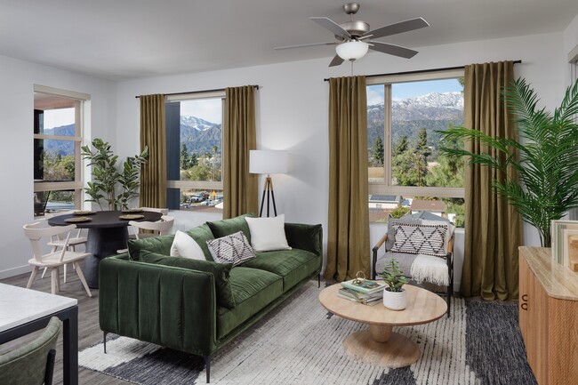 model living room with a green couch and a large window with a view of the mountains - Esperanza at Duarte Station