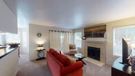 This single-floor residence offers a thoughtfully designed layout that balances comfort and functionality throughout its principal living spaces. The living room serves as the heart of the home, centered around a tile-surround fireplace with a white mantle that adds a classic focal point. Carpet flooring runs underfoot, while sliding glass doors open directly onto a private patio, filling the room with natural light and providing easy outdoor access. A second window further brightens the space.

The kitchen features rich wood cabinetry, dark granite countertops, and black appliances, including a full-size refrigerator. It opens seamlessly toward the dining area, which is defined by a striking bay window configuration that allows generous natural light to pour in. A round glass-top dining table sits beneath a brushed-metal pendant light, creating an elegant yet intimate setting.

Two bedrooms offer carpeted floors, ceiling fans, and windows with blinds that admit soft natural light. Each room provides comfortable proportions with ample wall space. The bathroom includes wood-look flooring, a full tub-shower combination with tile surround, dark granite vanity countertop, and warm-toned cabinetry. Throughout the residence, a neutral color palette and consistent finishes create a cohesive and inviting ambiance.