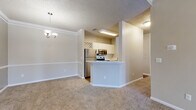Located at 4626 Summer Oak Ave E in Sarasota, Florida, this single-story home offers a well-organized, functional layout designed for comfortable everyday living. The open-concept living area is spacious and bright, featuring plush wall-to-wall carpeting, crown molding, a ceiling fan with light fixture, and a textured ceiling. Natural light enters through a front-facing window and entry door, contributing to an inviting atmosphere.

The kitchen is designed for efficiency, featuring a galley-style configuration with white cabinetry, white quartz-style countertops, and warm hardwood-style flooring. Stainless steel appliances—including a refrigerator, range, microwave, and dishwasher—are standard throughout. A peninsula with a sink separates the kitchen from the dining area, which is accented by a decorative chandelier and lattice cabinetry detail above.

The bedrooms are carpeted and each include ceiling fans, windows with blinds, and closet access. One bedroom connects directly to a walk-in closet with wire shelving, adjacent to a bathroom with a full soaking tub. A dedicated laundry area accommodates a full-size washer and dryer side by side with additional wire shelving above. Hallways provide practical storage access, completing the home's thoughtful design.