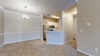 Located at 4626 Summer Oak Ave E in Sarasota, Florida, this single-story home offers a well-organized, functional layout designed for comfortable everyday living. The open-concept living area is spacious and bright, featuring plush wall-to-wall carpeting, crown molding, a ceiling fan with light fixture, and a textured ceiling. Natural light enters through a front-facing window and entry door, contributing to an inviting atmosphere.

The kitchen is designed for efficiency, featuring a galley-style configuration with white cabinetry, white quartz-style countertops, and warm hardwood-style flooring. Stainless steel appliances—including a refrigerator, range, microwave, and dishwasher—are standard throughout. A peninsula with a sink separates the kitchen from the dining area, which is accented by a decorative chandelier and lattice cabinetry detail above.

The bedrooms are carpeted and each include ceiling fans, windows with blinds, and closet access. One bedroom connects directly to a walk-in closet with wire shelving, adjacent to a bathroom with a full soaking tub. A dedicated laundry area accommodates a full-size washer and dryer side by side with additional wire shelving above. Hallways provide practical storage access, completing the home's thoughtful design.