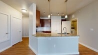 This single-story residence in Austin's 78750 zip code offers a well-organized layout across four bedrooms and two full bathrooms. The open-concept living and kitchen area serves as the heart of the home, anchored by a substantial granite-topped island with an integrated sink and pendant lighting overhead. The kitchen is outfitted with rich dark wood cabinetry, a subway tile backsplash, stainless steel appliances including a side-by-side refrigerator with ice maker, and a stainless range with microwave. A pantry with built-in shelving provides generous storage. The living area features gleaming hardwood-style flooring, track lighting, a ceiling fan, and multiple windows with access to an outdoor area, filling the space with natural light. Each bedroom is carpeted and equipped with a ceiling fan, offering a comfortable, quiet retreat. Both bathrooms feature tiled tub-shower combinations, hardwood-style flooring, granite vanity countertops, and dark wood cabinetry consistent with the home's overall design palette. A dedicated hallway with additional utility access and a closet rounds out the functional layout of this cohesive, move-in-ready home.