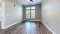 Located at 201 N Church St in Mooresville, NC, this well-appointed one-bedroom, one-bathroom unit offers a thoughtfully designed layout with modern finishes throughout. The open-concept kitchen and living area serves as the heart of the space, where the kitchen stands out with crisp white shaker cabinetry, granite countertops, a subway tile backsplash, and a full suite of stainless steel appliances including a French door refrigerator, electric range, microwave, and dishwasher. Pendant lighting over the kitchen peninsula adds a contemporary touch, while hardwood-style flooring runs seamlessly throughout the entire unit.

The living area is bright and welcoming, anchored by a ceiling fan and French doors topped with transom windows that invite natural light and provide outdoor access. The bedroom is a comfortable, well-sized retreat featuring large windows with blinds, a ceiling fan, and direct access to a hallway leading to the closet and bathroom. The closet offers wire shelving for organized storage. The bathroom is finished with a granite-topped vanity, white cabinetry, and a full tub-shower combination with clean white tile surround. Neutral gray walls and bold white trim create a cohesive, modern aesthetic throughout.