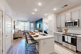 This single-story, two-bedroom, two-bathroom residence at 57 Caldwell Dr in Mount Holly, NC offers a thoughtfully designed layout that maximizes functionality and comfort. The open-concept kitchen serves as a central hub, featuring gray shaker-style cabinetry, white quartz countertops, a subway tile backsplash, stainless steel appliances, and a kitchen island with an undermount sink and bar seating—ideal for dining and entertaining. Wood-style plank flooring flows throughout the main living areas, lending warmth and continuity to the space.

The living room is bright and inviting, with large windows and access to a private exterior door, allowing abundant natural light and outdoor views. A ceiling fan adds comfort to this relaxed gathering space. Both bedrooms are well-proportioned, with large windows, plush carpeting, ceiling fans, and dedicated closets featuring wire shelving systems for organized storage.

Each bathroom is finished with gray cabinetry, quartz countertops, and wood-style flooring. The primary bathroom includes a walk-in shower and direct access to a spacious walk-in closet, while the secondary bathroom offers a tub-shower combination and an adjacent closet. A connecting hallway ties the layout together efficiently.