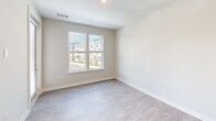 Located at 2213 Highland Forest Dr in Richmond, VA, this single-floor, one-bedroom, one-bathroom residence offers a thoughtfully designed layout with contemporary finishes throughout. Light gray wood-look flooring runs continuously across the entire space, complementing the neutral, soft-white walls that create a clean and cohesive aesthetic.

The kitchen is a standout feature, equipped with white shaker-style cabinetry extending to the ceiling, granite countertops, a single-basin sink, and a full suite of stainless steel appliances including a refrigerator, range, and over-the-range microwave. Recessed lighting illuminates the space effectively. An adjacent area provides a breakfast bar or pass-through counter that connects the kitchen to the living area.

The living room receives natural light through a large double window overlooking the surrounding community. The bedroom is a comfortable, private retreat with a ceiling fan, a generous window with outdoor views of a balcony railing and greenery, and access to a walk-in closet fitted with wire shelving.

The bathroom features a full tub-and-shower combination with brushed nickel fixtures, white tile surround, granite countertops, and direct access to the walk-in closet. A dedicated in-unit laundry closet with a stacked washer and dryer adds notable convenience to this efficient and modern residence.