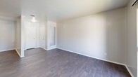 Located at 517 N Loop 288 in Denton, TX, this single-floor, 2-bedroom, 2-bathroom unit offers a practical and comfortable layout with thoughtful finishes throughout. The living room makes a strong first impression with rich, dark hardwood-style flooring, neutral gray walls, and a sliding glass door that opens to a private balcony overlooking a community pool area, filling the space with natural light and outdoor views. The galley-style kitchen is efficiently designed with warm wooden cabinetry, gray laminate countertops, a stainless steel double sink, and black appliances including a refrigerator, range, and dishwasher, all set atop matching hardwood-style flooring. Both bedrooms are carpeted for comfort and each features a ceiling fan with light fixture. The primary bedroom offers a well-sized layout, while the secondary bedroom includes a closet and a window with natural light. The two bathrooms are clean and functional — one features a full tiled tub-and-shower combination with chrome fixtures, while the other includes a white vanity, mirror, and dark hardwood-style flooring. A hallway connects the rooms, rounding out a cohesive and move-in-ready floor plan.
