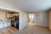 Located at 2304 Bob Wallace Ave SW in Huntsville, Alabama, this single-floor unit offers a practical and straightforward layout across three bedrooms, one bathroom, a kitchen, and a hallway with two closets. The living area features neutral-toned carpet and connects openly to the kitchen, which is outfitted with white cabinetry accented by wood-tone trim, a double-basin sink, and black appliances including an electric range, refrigerator, and over-the-range microwave. Light wood-style flooring runs through the kitchen, providing a clean contrast to the carpeted living space. A large front-facing window in the living area allows ample natural light to fill the room, complemented by a tiled entryway at the front door. Each bedroom is carpeted and features windows with horizontal blinds that bring in natural light. The primary bedroom is a comfortable size and includes a ceiling fan and a closet with sliding doors and built-in hanging storage. The additional bedrooms are similarly finished with neutral walls and carpet. The bathroom features a full tub and shower combination with white tile surround and accessibility grab bars. Textured ceilings are consistent throughout, and the overall color palette of warm grays and beige tones gives the space a clean, cohesive feel.