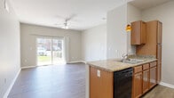 This single-floor, 2-bedroom, 2-bathroom residence offers a practical and comfortable layout designed for everyday living. The open-concept kitchen and living area serves as the heart of the home, where warm wood-toned cabinetry, granite-style countertops, a peninsula with a built-in sink, and a full suite of appliances — including a refrigerator, range, microwave, and dishwasher — create a functional and inviting space. Pendant lighting accents the kitchen peninsula, adding a subtle decorative touch. The living room is bright and airy, featuring durable hardwood-style flooring, a ceiling fan, and a large sliding glass door that floods the space with natural light and provides direct views of the surrounding green lawn and community exterior. Both bedrooms offer plush carpeting and ample closet space, with the primary bedroom featuring a spacious walk-in style closet. The second bedroom benefits from a large window that brings in natural light. Each bathroom is finished with tile flooring, warm wood vanity cabinetry, a single sink, and well-lit mirrors. Neutral, warm-toned walls throughout lend a clean and cohesive aesthetic to the entire residence.