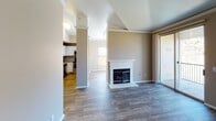 This single-floor residence offers a thoughtfully designed layout that balances comfort and functionality throughout. The open living area serves as the heart of the home, anchored by a classic white-mantled fireplace and finished with wood-style plank flooring that extends seamlessly through the main spaces. Decorative columns frame the transition between the living area and the kitchen, adding an architectural detail that enhances the overall design.

The kitchen is well-equipped with white shaker-style cabinetry, granite-look countertops, stainless steel appliances including a refrigerator, range, microwave, and dishwasher, and a double basin sink. Warm hardwood-tone flooring completes the space, making it both practical and visually appealing.

A sliding glass door leads from the living area to a private balcony that overlooks an open, natural landscape, providing an abundance of natural light and scenic outdoor views. The bedroom spaces offer a quieter retreat, with plush carpeting, ceiling fans, and windows framing the surrounding terrain.

A full bathroom includes a tiled tub-shower combination, granite-top vanity, and wood-style flooring. A dedicated in-unit laundry room houses a full-size washer and dryer with overhead shelving for added storage. Throughout, neutral tones and crown molding lend a clean, cohesive aesthetic.
