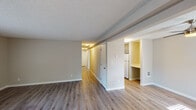 Located at 18540 SW Boones Ferry Rd in Tualatin, Oregon, this single-floor unit offers a clean, updated interior designed for comfortable everyday living. Throughout the space, durable wood-look luxury vinyl plank flooring provides a warm, cohesive aesthetic, complemented by neutral beige walls and crisp white trim and baseboards. Textured ceilings add a classic finishing touch across the main living areas.

The open living area is generously proportioned, offering flexible furniture arrangements and a bright, airy feel. A hallway connects the main living space to the private rooms, with natural light filtering in through windows near the entryway. The entry area features two interior doors and a window, creating a welcoming transition into the home.

The kitchen, visible from the living area, is equipped with white appliances and cabinetry, providing functional workspace for daily use. The bedroom is a comfortable, well-sized room featuring a full-width sliding closet with mirrored panels, maximizing both storage and the sense of space.

The bathroom is tastefully finished with gray shaker-style cabinetry, a white quartz countertop, a undermount sink with brushed nickel fixtures, a large wall mirror, and a full tub-shower combination. The overall design is clean and move-in ready, reflecting a thoughtful, practical approach to residential living.