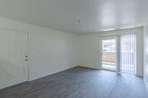 This 1-bedroom, 1-bathroom unit is thoughtfully laid out across a single floor, offering a functional and comfortable living environment. The combined kitchen and living room area forms the heart of the unit, featuring light hardwood-style flooring that runs throughout the main spaces. The kitchen is equipped with light wood cabinetry, a gas range, built-in microwave, refrigerator, and a peninsula countertop that separates the cooking area from the living space. A notable convenience is the in-unit washer located just off the kitchen. The living room is bright and airy, with a sliding glass door fitted with vertical blinds that opens to a private balcony, allowing natural light to fill the space. The bedroom features plush carpeting, a ceiling fan, and a window with vertical blinds. It is complemented by a spacious walk-in closet outfitted with wire shelving and hanging rods, providing ample storage. The full bathroom includes a tub-shower combination, a toilet, and a vanity with light wood cabinetry, a single sink, and a large mirror with overhead lighting. Light-toned walls and hardwood-style flooring throughout lend the unit a clean, cohesive aesthetic.