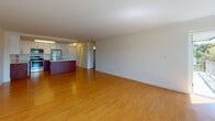 This single-floor residence at 1400 Worcester Rd in Framingham, Massachusetts, offers a well-designed open-concept layout with consistent hardwood flooring throughout. The spacious living and dining area is bathed in natural light through large windows that frame outdoor views of surrounding greenery, complemented by baseboard heating and crown molding details that lend a polished finish to the space.

The kitchen is thoughtfully appointed with a striking two-tone design featuring rich wood lower cabinetry paired with sleek high-gloss white upper cabinets. Stainless steel appliances, including a range, microwave, and dishwasher, are integrated alongside light quartz-style countertops and a stainless undermount sink, creating a functional and contemporary cooking space. A kitchen island adds additional prep and serving versatility.

The bedroom is generously proportioned, featuring crown molding, hardwood floors, and a built-in closet system complete with shelving and drawers, offering ample and organized storage. A second room with hardwood flooring and a window with outdoor views provides flexible use as an additional bedroom or living space.

Two full bathrooms mirror each other in design, each featuring a soaking tub with a tiled shower surround, a curved shower rod, marble-look tile flooring, and a white vanity, delivering a clean and cohesive aesthetic throughout.