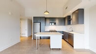Located in the vibrant H Street corridor of Washington, DC, this three-bedroom, one-bathroom unit offers a thoughtfully designed modern interior. The open-concept kitchen and living area serves as the heart of the home, featuring sleek slate-gray cabinetry, white subway tile backsplash, stainless steel appliances, and a central island with a crisp white countertop — all beneath elevated ceilings with recessed and pendant lighting. Light wood-tone flooring flows throughout, unifying the space with a clean, contemporary aesthetic. Each of the three bedrooms is bright and airy, benefiting from large floor-to-ceiling windows with black frames that frame sweeping elevated views of the surrounding Washington, DC cityscape and tree canopy. The primary bedroom is generously proportioned and bathed in natural light through a wide bank of windows. A third bedroom features a glass-paneled interior door, adding an open, modern touch. The bathroom is clean and functional, finished with large-format white wall tiles, a soaking tub and shower combo, and brushed nickel fixtures. A dedicated closet rounds out the layout, providing practical storage. The overall ambiance is contemporary, bright, and move-in ready.