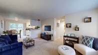 This single-floor residence offers three bedrooms and one bathroom within a efficiently designed, comfortable layout. The open-concept living, dining, and kitchen area forms the heart of the home, with light neutral walls, carpet flooring, and natural light streaming in through a sliding glass door in the dining area that leads to an outdoor patio. The living room provides a bright, welcoming space with wall-mounted shelving accents, while the adjacent dining area comfortably accommodates a full dining set. The galley-style kitchen is well-equipped, featuring white cabinetry, dark appliances including a range and refrigerator, a dishwasher, tile flooring, and ample counter and storage space. A hallway connects the living area to the three bedrooms, each finished with carpet flooring and sliding-door closets offering practical storage. The primary bedroom is a comfortably sized retreat with room for a full bedroom suite. The full bathroom includes a tub-shower combination with tile flooring. A dedicated laundry room houses a full-size washer and dryer alongside overhead cabinetry, adding significant convenience to daily living. Throughout, the home maintains a clean, neutral palette that creates a cohesive and inviting atmosphere.