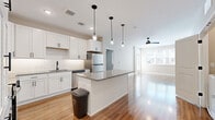 Located at 500 N Henry in Williamsburg, Virginia, this well-appointed 2-bedroom, 2-bathroom residence offers a thoughtfully designed single-floor layout with modern finishes throughout. The open-concept kitchen and living area forms the heart of the home, showcasing white shaker cabinetry, granite countertops, a subway tile backsplash, and stainless steel appliances including a refrigerator, range, and microwave. A central island with pendant lighting provides additional prep space and serves as a natural gathering point, while the living area beyond features recessed lighting, a ceiling fan, and large windows that invite abundant natural light. Gleaming hardwood-style flooring flows seamlessly across the entire residence, enhancing the bright, cohesive aesthetic. The primary bedroom offers a comfortable footprint with its own ceiling fan, a window with exterior views, and direct access to a private bathroom. The second bedroom is equally well-lit, with a ceiling fan and generous natural light. Both bathrooms are finished with granite-topped white vanities, wood-look flooring, and matte black hardware accents. Four closets provide ample storage throughout the home, rounding out this clean, contemporary residence in the heart of Williamsburg.