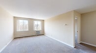 This single-floor, one-bedroom, one-bathroom unit offers a practical and efficient layout across a comfortable footprint. The space is finished in soft, neutral tones throughout, creating a clean and cohesive aesthetic from room to room.

The kitchen is well-equipped, featuring warm wood cabinetry with ample upper and lower storage, light laminate countertops, a double-basin sink, and white appliances including an electric range and refrigerator. A ceiling light fixture brightens the space, which is laid with durable tile flooring. Adjacent to the kitchen, a closet with louvered doors provides convenient storage.

A carpeted hallway connects the main areas, leading to a spacious living area that receives generous natural light through a pair of windows overlooking the surrounding neighborhood. Baseboard heating ensures year-round comfort, and the open, neutral walls offer versatile possibilities for personalization.

The bedroom is a well-proportioned, private retreat with soft carpet underfoot, a window offering natural light, and baseboard heating. Its simple, clean design provides flexibility for various furniture arrangements.

The bathroom is neatly appointed with white tile surrounding a full tub-shower combination, tile flooring, a wood-toned vanity with a granite-style countertop, and standard fixtures — all presented in a bright, clean finish.