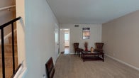 Located at 4031 7 Oaks Ln in East Point, Georgia, this two-story home offers a practical and comfortable layout across both levels. The main level features a carpeted living area with neutral-toned walls, a textured ceiling, and easy access to additional rooms via a connecting doorway. A staircase with a metal railing leads to the upper level, providing a clear sense of the home's vertical flow. The kitchen is outfitted with rich, dark cabinetry, black appliances including a refrigerator, electric range, and dishwasher, complemented by light countertops and hardwood-style flooring that adds warmth to the space. The bedrooms are carpeted and well-sized, with neutral walls that create a calm atmosphere. At least one bedroom features a closet with built-in shelving and a window that allows natural light to filter in. The bathroom includes a tub-shower combination. Throughout the home, consistent neutral tones, carpet flooring in living and sleeping areas, and visible HVAC vents reflect a straightforward, functional design. The overall layout is well-organized and suited for everyday living in the East Point community.