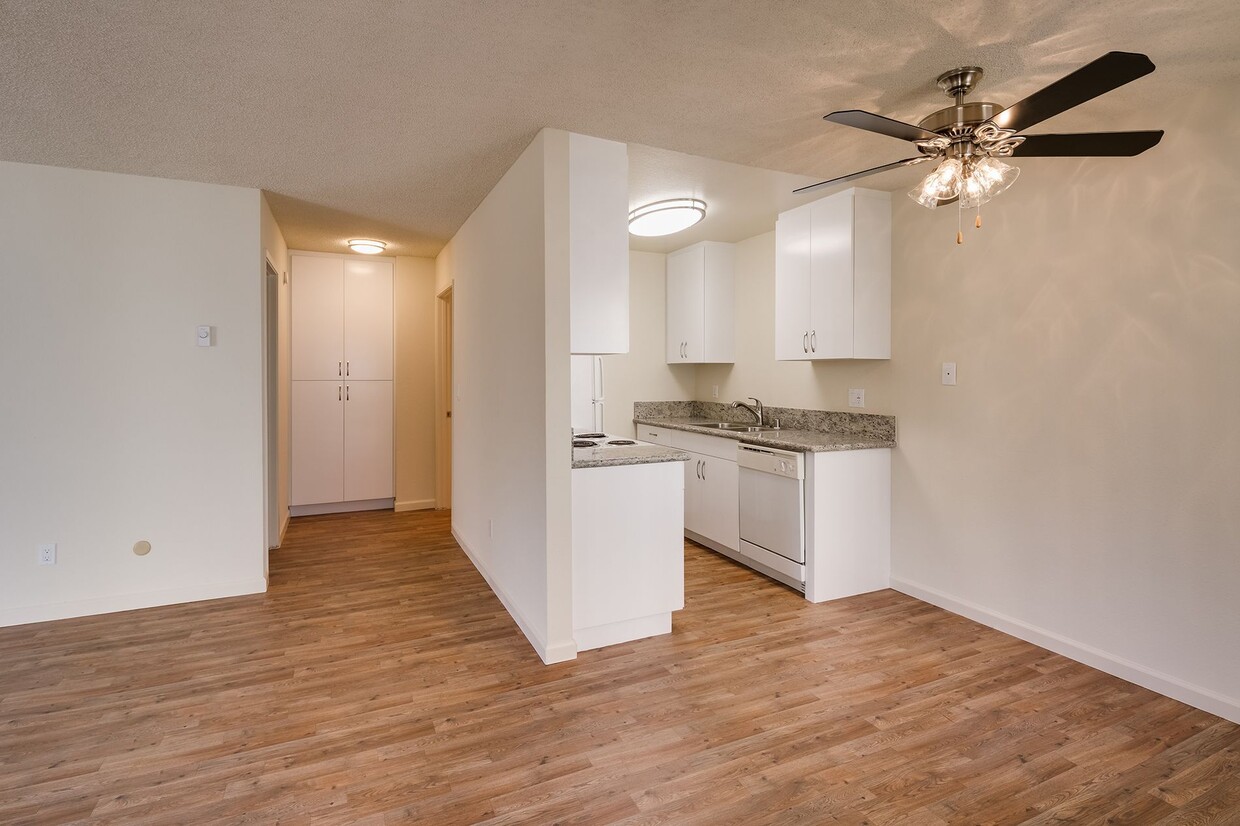 Cocina con gabinetes blancos, encimeras de formica, pisos de tablones estilo madera, y la vista del área del comedor. - Casa De La Mesa