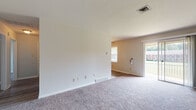 This single-floor residence offers a well-organized layout designed for comfortable everyday living. The spacious living area is finished with soft, neutral-toned carpeting and features a sliding glass door that opens to a covered outdoor balcony framed by classic brick exterior walls, allowing natural light to filter into the room. A secondary living or dining area connects seamlessly, also carpeted and illuminated by a window with views of the surrounding exterior.

The kitchen is equipped with warm-toned wood cabinetry, ample upper and lower storage, a double-basin stainless steel sink, a textured laminate countertop, a tile backsplash, and a white electric range. Light wood-style flooring grounds the space, and a window provides natural brightness throughout.

The residence includes two bedrooms, both featuring plush carpeting and neutral wall tones. The first bedroom offers a built-in closet with bifold doors and shelving, while the second includes a standard closet and a window that brings in generous natural light. Each room benefits from ceiling ventilation for climate control.

The bathroom showcases a classic black-and-white tile design, with white square wall tiles accented by bold black border tiles, complementing the full-sized bathtub and toilet. Overall, the space presents a clean, functional, and move-in ready environment.