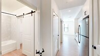 Located at 1701 N Florida Ave in Tampa, FL, this thoughtfully designed one-bedroom, one-bathroom unit maximizes every square foot with a clean, modern aesthetic. Light wood-look flooring runs throughout, complemented by crisp white walls and matte black hardware accents that create a cohesive, contemporary feel.

The combined kitchen and living area serves as the heart of the unit. The galley-style kitchen is well-appointed with white shaker cabinetry, quartz countertops, a white subway tile backsplash, stainless steel appliances including a range, microwave, and refrigerator, and a deep single-basin sink with an industrial-style faucet. Sliding barn doors add a stylish architectural detail along the main corridor, adding character while optimizing space.

The bedroom is a bright, comfortable retreat featuring a ceiling fan, large windows that invite natural light, and access to a closet. Three closets in total provide ample storage throughout the unit.

The bathroom offers a clean, spa-inspired finish with a soaking tub and shower combo, large-format hexagonal tile surround, a quartz-topped vanity, and matte black fixtures. A dedicated laundry area and a defined entryway further enhance the unit's practical layout, making this an efficient and stylish urban residence.