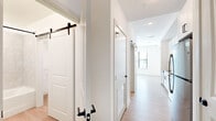 Located at 1701 N Florida Ave in Tampa, FL, this thoughtfully designed one-bedroom, one-bathroom unit maximizes every square foot with a clean, modern aesthetic. Light wood-look flooring runs throughout, complemented by crisp white walls and matte black hardware accents that create a cohesive, contemporary feel.

The combined kitchen and living area serves as the heart of the unit. The galley-style kitchen is well-appointed with white shaker cabinetry, quartz countertops, a white subway tile backsplash, stainless steel appliances including a range, microwave, and refrigerator, and a deep single-basin sink with an industrial-style faucet. Sliding barn doors add a stylish architectural detail along the main corridor, adding character while optimizing space.

The bedroom is a bright, comfortable retreat featuring a ceiling fan, large windows that invite natural light, and access to a closet. Three closets in total provide ample storage throughout the unit.

The bathroom offers a clean, spa-inspired finish with a soaking tub and shower combo, large-format hexagonal tile surround, a quartz-topped vanity, and matte black fixtures. A dedicated laundry area and a defined entryway further enhance the unit's practical layout, making this an efficient and stylish urban residence.