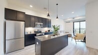 This contemporary 750 square foot apartment in Oakdale, MN, offers a harmonious blend of style and functionality. The open-concept design seamlessly integrates the kitchen and living areas, creating a spacious feel. The kitchen boasts sleek dark cabinetry, stainless steel appliances, and a generous island, perfect for meal prep and casual dining.

Both bedrooms are well-appointed, with the primary bedroom measuring 110 square feet. Large windows in the bedrooms provide ample natural light and scenic views. The two bathrooms feature modern fixtures, including a combination tub-shower, floating vanities, and stylish tile work.

The living area is adorned with comfortable seating and tasteful artwork, while sliding glass doors lead to a balcony, offering outdoor space and views. Light wood-look flooring runs throughout, complementing the crisp white walls and adding warmth to the space.

Practical amenities include in-unit laundry with stacked washer and dryer, ensuring convenience for residents. The apartment's thoughtful design maximizes the use of space, with clever storage solutions integrated throughout.

Located at 7600 2nd St N in Oakdale, this apartment combines urban comfort with a touch of nature, evident in the views from its windows. The modern finishes, functional layout, and attention to detail make this space an ideal home for those seeking contemporary living in a prime location.