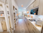 This 330 square foot studio apartment maximizes space efficiency through a thoughtful open-concept design. The bedroom area features a comfortable bed, large window with city views, and a circular mirror adding depth to the space. A small work area with a laptop-friendly table is seamlessly integrated.

The living space is multifunctional, with a sleek entertainment unit housing a large TV and storage. Natural light floods the area through expansive windows, complementing the warm wood tones of the furniture.

The kitchen, while compact, is fully equipped with modern appliances including a refrigerator, microwave, and cooktop. Light-colored cabinetry and countertops contribute to a bright, airy feel.

The bathroom showcases a glass-enclosed shower, toilet, and built-in storage solutions. A neutral color palette and wood-look flooring unify the space, creating a cohesive and contemporary ambiance throughout the apartment.