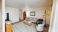 Located at 110 S Almon St in Moscow, Idaho, this well-organized two-bedroom, one-bathroom unit offers a practical and comfortable layout across a single floor. The living room serves as the heart of the space, featuring light hardwood-style flooring, neutral walls, and a sliding glass door that opens onto a private balcony with views of the surrounding neighborhood. A wall-mounted A/C unit and baseboard heating ensure year-round comfort. The kitchen is efficiently designed with warm wood cabinetry, light marble-style countertops, a stainless steel sink, and white appliances, providing all the essentials in a compact footprint. A hallway lined with open built-in shelving connects the main living areas and adds convenient storage. The primary bedroom is a comfortable retreat with plush carpet, a natural window, and ample space. The second bedroom, also carpeted, includes a built-in open closet and a window that brings in natural light. The bathroom features a tub-shower combination adorned with distinctive multi-toned tile work in soft sage green and warm blush tones, adding a touch of character. A dedicated closet provides additional storage. The unit's clean, white interior and practical design make it a functional home in a residential Moscow neighborhood.