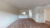 This single-story residence is laid out to maximize functionality across its interconnected rooms. The living area is generously sized, finished with wall-to-wall beige carpeting and neutral white walls that create a bright, open atmosphere. A pass-through window connects the living area directly to the kitchen, providing convenient sightlines and an open feel between the two spaces.

The kitchen is arranged in a U-shaped configuration, offering ample cabinetry with white upper and lower cabinets featuring brushed-metal hardware. Countertops with a warm earth-toned finish run along three walls, complemented by a stainless steel sink positioned beneath a window that brings in natural light. A white electric range with overhead ventilation hood anchors the cooking area, while tile flooring with a subtle pattern completes the space.

The bedrooms are carpeted and feature neutral walls, ceiling fans with integrated light fixtures, and natural light from windows fitted with horizontal blinds. At least one bedroom includes a sliding-door closet, and another provides access to a dedicated walk-in or secondary closet area. A hallway connects the bedrooms to the rest of the unit.

The bathroom is outfitted with a full tub and shower combination, white square tile surround, a granite-topped vanity, and tile flooring, presenting a clean and practical design throughout.