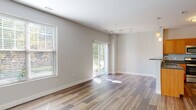 Located at 30 Seven Springs Lane in Burlington, MA, this single-floor residence presents a clean, contemporary design characterized by neutral tones, wood-style plank flooring, and an open layout that connects key living areas seamlessly.

The living room is a generously proportioned space bathed in natural light, courtesy of large windows fitted with blinds and a sliding glass door that opens to an outdoor view. Track lighting overhead adds functional versatility, while the soft gray walls create a calm, neutral backdrop throughout.

The kitchen is well-equipped with warm-toned cabinetry, dark granite countertops, a glass tile backsplash, and a full suite of stainless steel appliances including a range, microwave, dishwasher, and refrigerator. A peninsula with pendant lighting above connects the kitchen to the main living area, enhancing the open-concept flow.

Bedrooms continue the consistent flooring and neutral palette, with windows providing natural light and outdoor views. At least one bedroom features access to a walk-in closet, offering practical storage.

The bathroom is finished with tile flooring, a warm wood vanity, dark granite countertop, a backlit mirror, and a full tub-shower combination, delivering a clean and functional design.