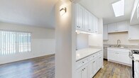 Located at 6645 Woodman Ave in Van Nuys, CA, this 2-bedroom, 2-bathroom residence offers a thoughtfully designed single-floor layout with modern updates throughout. Rich hardwood-style flooring flows seamlessly across the living room, hallway, kitchen, and bedrooms, creating a warm and cohesive aesthetic.

The living room is bright and open, featuring large windows with vertical blinds and a sliding glass door that leads directly to a private balcony, allowing ample natural light to fill the space. A well-placed wall sconce adds accent lighting near the kitchen entry.

The kitchen is a standout feature, boasting crisp white shaker cabinetry with brushed nickel hardware, elegant marble-look quartz countertops, and a full suite of stainless steel appliances including a gas range, over-the-range microwave, and dishwasher. A peninsula provides additional counter space and reinforces the kitchen's functional design.

Both bedrooms are generously proportioned, with the primary bedroom offering a spacious layout, a large closet with mirrored sliding doors, and a dedicated bathroom. Clean white walls and wood-tone flooring give each bedroom a calm, neutral atmosphere.

The bathrooms are finished with white vanity cabinetry, stone-look countertops, large mirrors, and glass-enclosed shower-tub combinations with tile flooring, delivering a clean and polished look throughout.