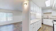 Located at 6645 Woodman Ave in Van Nuys, CA, this 2-bedroom, 2-bathroom residence offers a thoughtfully designed single-floor layout with modern updates throughout. Rich hardwood-style flooring flows seamlessly across the living room, hallway, kitchen, and bedrooms, creating a warm and cohesive aesthetic.

The living room is bright and open, featuring large windows with vertical blinds and a sliding glass door that leads directly to a private balcony, allowing ample natural light to fill the space. A well-placed wall sconce adds accent lighting near the kitchen entry.

The kitchen is a standout feature, boasting crisp white shaker cabinetry with brushed nickel hardware, elegant marble-look quartz countertops, and a full suite of stainless steel appliances including a gas range, over-the-range microwave, and dishwasher. A peninsula provides additional counter space and reinforces the kitchen's functional design.

Both bedrooms are generously proportioned, with the primary bedroom offering a spacious layout, a large closet with mirrored sliding doors, and a dedicated bathroom. Clean white walls and wood-tone flooring give each bedroom a calm, neutral atmosphere.

The bathrooms are finished with white vanity cabinetry, stone-look countertops, large mirrors, and glass-enclosed shower-tub combinations with tile flooring, delivering a clean and polished look throughout.