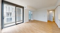 Located on the 10th floor at 707 Terry Ave in Seattle's First Hill neighborhood, this modern one-bedroom, one-bathroom residence offers a thoughtfully designed layout with clean, contemporary finishes throughout. Light-toned hardwood flooring flows seamlessly across the entire unit, complementing the crisp white walls and creating a bright, cohesive aesthetic.

The open-concept living, dining, and kitchen area serves as the heart of the home. The sleek kitchen features flat-front white cabinetry, stone countertops, and a full suite of stainless steel appliances, including a built-in oven, microwave, and refrigerator. Floor-to-ceiling sliding glass doors invite abundant natural light and open directly onto a private balcony with urban skyline views.

The living area extends generously toward a second set of sliding glass doors, further enhancing the sense of openness and connectivity to the outdoors. The bedroom is a calm, well-proportioned retreat with a built-in closet featuring sliding panel doors and its own access to an outdoor space, offering additional natural light and fresh air.

The bathroom is finished with clean white tile, a glass-enclosed walk-in shower, a soaking tub, and polished chrome fixtures. A dedicated laundry area and hallway with additional storage complete this well-appointed urban residence.