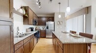 Located at 9580 Ridgegate Pkwy in Lone Tree, CO, this well-appointed one-bedroom, one-bathroom residence offers a thoughtfully designed single-level layout. The open-concept kitchen and living area serves as the heart of the home, featuring rich wood cabinetry, granite countertops, stainless steel appliances, and pendant lighting over a central island with bar seating. Hardwood-style flooring flows throughout the kitchen and living areas, adding warmth and continuity.

The living room is bright and inviting, highlighted by large windows that flood the space with natural light and offer outdoor views of the surrounding greenery. A built-in shelving nook provides a functional workspace or display area adjacent to the main living space.

The carpeted bedroom is generously sized, featuring a ceiling fan, large windows with outdoor views, and direct access to a dedicated walk-in closet with shelving and hanging storage. The full bathroom is well-appointed with a dual-sink vanity topped with granite, wood cabinetry, and a full shower-tub combo with tiled surround.

A dedicated in-unit laundry closet with full-size washer and dryer hookups and overhead shelving adds everyday convenience. Neutral tones throughout create a calm, cohesive ambiance.