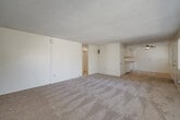Located at 6595 Montezuma Rd in San Diego, CA, this single-floor, 2-bedroom, 2-bathroom unit offers a functional and well-organized layout. The open-concept living and dining area is generously sized, featuring neutral-toned carpet, a textured ceiling, and a ceiling fan with integrated light fixture. Large windows along the exterior wall flood the space with natural light and offer views of the surrounding outdoor greenery.

The kitchen is efficiently designed with white cabinetry, a peninsula cooktop island, a double-basin sink, a dishwasher, a refrigerator, and ample upper and lower cabinet storage. Wood-look flooring in the kitchen provides a clean contrast to the carpeted living areas.

The primary bedroom is a comfortable, well-proportioned room with carpeted flooring, a window for natural light, and dedicated closet space. The second bedroom is similarly appointed, offering a bright and versatile space. Three closets throughout the unit provide excellent storage capacity.

Both bathrooms are clean and straightforward, featuring tub-shower combinations with white tile surrounds. A hallway connects the main living spaces to the bedrooms and bathrooms, contributing to the unit's practical flow. The overall aesthetic is light, neutral, and move-in ready.