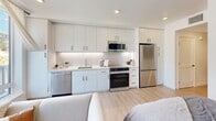 This 350 square foot studio apartment in Santa Cruz, CA offers a thoughtfully designed living space on a single floor. The open-concept layout maximizes the use of space, seamlessly blending the living area, kitchen, and sleeping quarters. The living room boasts large windows that flood the space with natural light and provide stunning city views. The modern kitchen is equipped with stainless steel appliances, ample cabinetry, and a sleek countertop, perfect for preparing meals. The sleeping area, while not separated by walls, is comfortably accommodated within the studio's layout. The bathroom features a clean, contemporary design with a shower/tub combination and wood-look flooring that extends throughout the apartment. The neutral color palette, predominantly whites and grays, creates a bright and airy atmosphere. Strategic lighting and minimalist decor enhance the sense of spaciousness in this compact yet functional urban dwelling.