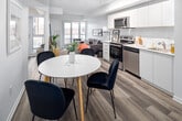 Located in Toronto's vibrant Roncesvalles neighbourhood, Unit 223 at 2376 Dundas Street West is a well-designed one-bedroom suite that maximizes its footprint through a thoughtful open-concept layout. The unit features light hardwood-style flooring throughout, crisp white walls, and a neutral palette that creates a cohesive and airy feel across all living spaces.

The kitchen runs along one wall of the main living area and is outfitted with flat-front white cabinetry extending to the ceiling, a white subway tile backsplash, light countertops, and a full suite of stainless steel appliances including a refrigerator, electric range, built-in microwave, and dishwasher. Track lighting overhead provides focused task illumination. The kitchen flows directly into the dining area, which comfortably fits a round table and chairs, and the living room beyond, where a large sliding glass door draws in natural light and provides access to a balcony.

The bedroom is a well-proportioned private retreat featuring a sliding-door closet and room for a full furniture arrangement. The bathroom includes a full tub-shower combination with neutral tile surround. A dedicated entryway with a patterned mat completes the unit's functional layout, making efficient use of every square foot in this modern urban residence.