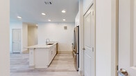 This single-story, 3-bedroom, 3-bathroom home offers a thoughtfully designed layout with a clean, contemporary aesthetic. The open-concept kitchen and living area serves as the heart of the home, featuring white shaker-style cabinetry that extends to the ceiling, a granite-topped island with an undermount sink, stainless steel appliances including a French door refrigerator and microwave, and recessed lighting — all set over light wood-style flooring that runs throughout the main living spaces.

Each of the three bedrooms is carpeted for comfort and includes its own dedicated closet, with the primary bedroom offering a walk-in closet with built-in shelving and hanging rods. The primary bedroom also features a ceiling fan, multiple windows allowing generous natural light, and direct access to a private outdoor area. Secondary bedrooms are similarly bright, with wide windows framing outdoor views and ceiling fans for climate comfort.

The three bathrooms maintain a consistent, modern design with stone-topped vanities, white cabinetry, and wood-look plank flooring. At least one bathroom includes a soaking tub with full-height gray tile surround. A hallway connects the bedroom wing, and three dedicated closets provide ample storage throughout the home. The overall ambiance is light, neutral, and move-in ready.