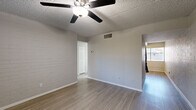 Located at 615 S Hardy Dr in Tempe, Arizona, this 2-bedroom, 1-bathroom single-story home offers a practical and well-appointed layout. The interior features light wood-style flooring throughout, painted brick accent walls that add texture and character to multiple rooms, and textured ceilings with ceiling fans in each main living space for year-round comfort.

The combined kitchen and living area serves as the heart of the home. The kitchen is outfitted with white shaker cabinetry, a white subway tile backsplash, and a full suite of stainless steel appliances including a dishwasher, electric range, and over-the-range microwave, complemented by a black refrigerator. A window provides natural light to the kitchen and dining area.

Both bedrooms are comfortably sized, each featuring the same wood-style flooring, painted brick accent walls, ceiling fans with lighting, and windows fitted with horizontal blinds that let in natural light while maintaining privacy. The primary bedroom includes a closet for added storage.

The bathroom is clean and bright, featuring a modern vanity with a white countertop and wood-toned cabinetry, a full tub-shower combination with white tile surround, and wood-style flooring that ties the space together cohesively. A hallway connects the bedrooms and bathroom, completing the efficient single-floor layout.