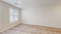 This single-floor unit offers a thoughtfully designed layout that maximizes functionality across its well-proportioned floor plan. The combined kitchen and living area serves as the heart of the home, anchored by a kitchen outfitted with white shaker cabinetry featuring matte black hardware, granite countertops, a farmhouse-style sink, subway tile backsplash, and stainless steel appliances including a range, microwave, and refrigerator. A central island with pendant lighting above provides additional prep and gathering space. Light wood-look flooring runs throughout the main living areas, contributing to a clean, contemporary aesthetic.

The bedroom is a comfortable size, featuring plush carpeting, a ceiling fan with light fixture, and a window that allows natural light to filter in. It connects to a generously sized walk-in closet equipped with wire shelving and hanging rods along multiple walls, offering ample storage. The bathroom includes a granite-topped vanity with white cabinetry, a framed mirror, and built-in wire shelving for additional storage. A dedicated laundry room with wood-look flooring and wire shelving completes the unit's practical amenities.