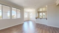 Located at 3250 Market St in Riverside, CA, this well-appointed single-story home offers three bedrooms and two bathrooms across a comfortable and thoughtfully designed floor plan. The open-concept living and dining area is bathed in natural light streaming through multiple large windows, and features warm wood-style plank flooring and elegant crown molding. A chandelier anchors the dining space, adding a refined touch to the layout.

The kitchen is outfitted with rich wood cabinetry, granite countertops, stainless steel appliances including a gas range and built-in microwave, and a breakfast bar that connects seamlessly to the main living area. Views of lush palm trees are visible through the kitchen window, adding a distinctly Southern California character.

The bedrooms are carpeted for comfort, with the primary bedroom offering generous proportions and French doors that open to a private balcony with outdoor views. Additional bedrooms include closets with built-in shelving. Two hallways and two closets provide ample storage throughout.

The bathrooms feature wood-style flooring, granite-topped vanities with warm wood cabinetry, and a full tub-shower combination. The walk-in closet includes wraparound wire shelving, maximizing storage efficiency. The overall aesthetic is clean, neutral, and move-in ready.