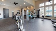 Located at 1001 Linger Longer Dr in Summerville, SC, this single-floor fitness center is designed to support a comprehensive workout experience. The space is generously proportioned, with soaring ceilings and an abundance of large windows that flood the interior with natural light and offer views of the surrounding community. Ceiling fans are distributed throughout, contributing to a comfortable environment during exercise.

The main workout area is outfitted with a strong selection of Inflight Fitness strength machines, including cable stations, leg press, and isolation equipment, all arranged to allow ample space for movement between stations. A dedicated free weights zone features a tiered dumbbell rack stocked with a full range of weights, accompanied by full-length wall mirrors that enhance the sense of space and assist with proper form. Stability balls, resistance bands, medicine balls, and exercise mats are also available, supporting functional and flexibility training.

A separate cardio area houses treadmills, an elliptical, and a stationary bike, positioned beneath large windows with a wall-mounted television for entertainment during workouts. Rubber flooring throughout the facility provides both safety and durability. A motivational "Stronger Than Yesterday" wall graphic reinforces the energetic atmosphere. The layout is thoughtfully organized, offering a well-rounded facility suitable for users of all fitness levels.