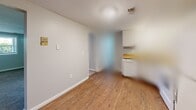 Located at 1717 Kuntz Rd in Erie, Pennsylvania, this single-floor, two-bedroom, one-bathroom unit offers a straightforward and functional layout. The space features neutral gray walls, white trim, and textured ceilings throughout, creating a clean and consistent aesthetic. Both bedrooms are carpeted in a warm beige tone and receive natural light through windows that look out to surrounding greenery, lending each room a bright and comfortable feel. The primary bedroom is generously sized, providing ample space for furnishings, while the second bedroom offers a similarly open and versatile layout. The kitchen is efficiently designed with white cabinetry, light wood-toned countertops arranged in an L-shape, a double-coil electric range, a refrigerator, and a single-basin sink — all positioned to maximize usability within the space. Hardwood-style flooring runs through the kitchen and connecting areas, adding warmth and durability. A hallway connects the main living areas to the full bathroom, which includes a tub-shower combination, toilet, vanity with storage, and hardwood-style flooring. The overall layout, as shown in the dollhouse view, is compact yet well-organized, making efficient use of every square foot this Erie-area unit has to offer.