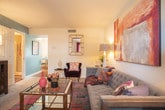 This two-floor residence in Newport News, Virginia offers a well-organized layout filled with colorful, contemporary design throughout. The living room serves as a welcoming centerpiece, featuring plush carpeting, bold abstract wall art, and an eclectic mix of seating that includes a tufted gray sofa, deep plum accent chairs, and a warm mustard lounge chair — all anchored by a vibrant, multicolored area rug and a glass-top coffee table.

The kitchen is outfitted with warm wood cabinetry, dark countertops, black appliances, and hardwood-style flooring. A bold magenta accent wall adds a striking visual element, while a peninsula provides additional workspace and casual dining potential. Natural light filters in through a window, brightening the space.

The primary bedroom features a dramatic charcoal accent wall, soft carpeting, and a generously sized upholstered headboard. A second bedroom showcases a vivid teal accent wall paired with bright, cheerful bedding and natural light from a window with sheer curtains. A third bedroom offers a neutral, serene palette with soft carpet and framed wall art.

Bathrooms include a full bath with a tub-shower combination and tile flooring, as well as a powder room with a classic pedestal sink and hardwood-style floors, adding a refined touch to the home's overall design.
