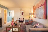 This two-floor residence in Newport News, Virginia offers a well-organized layout filled with colorful, contemporary design throughout. The living room serves as a welcoming centerpiece, featuring plush carpeting, bold abstract wall art, and an eclectic mix of seating that includes a tufted gray sofa, deep plum accent chairs, and a warm mustard lounge chair — all anchored by a vibrant, multicolored area rug and a glass-top coffee table.

The kitchen is outfitted with warm wood cabinetry, dark countertops, black appliances, and hardwood-style flooring. A bold magenta accent wall adds a striking visual element, while a peninsula provides additional workspace and casual dining potential. Natural light filters in through a window, brightening the space.

The primary bedroom features a dramatic charcoal accent wall, soft carpeting, and a generously sized upholstered headboard. A second bedroom showcases a vivid teal accent wall paired with bright, cheerful bedding and natural light from a window with sheer curtains. A third bedroom offers a neutral, serene palette with soft carpet and framed wall art.

Bathrooms include a full bath with a tub-shower combination and tile flooring, as well as a powder room with a classic pedestal sink and hardwood-style floors, adding a refined touch to the home's overall design.